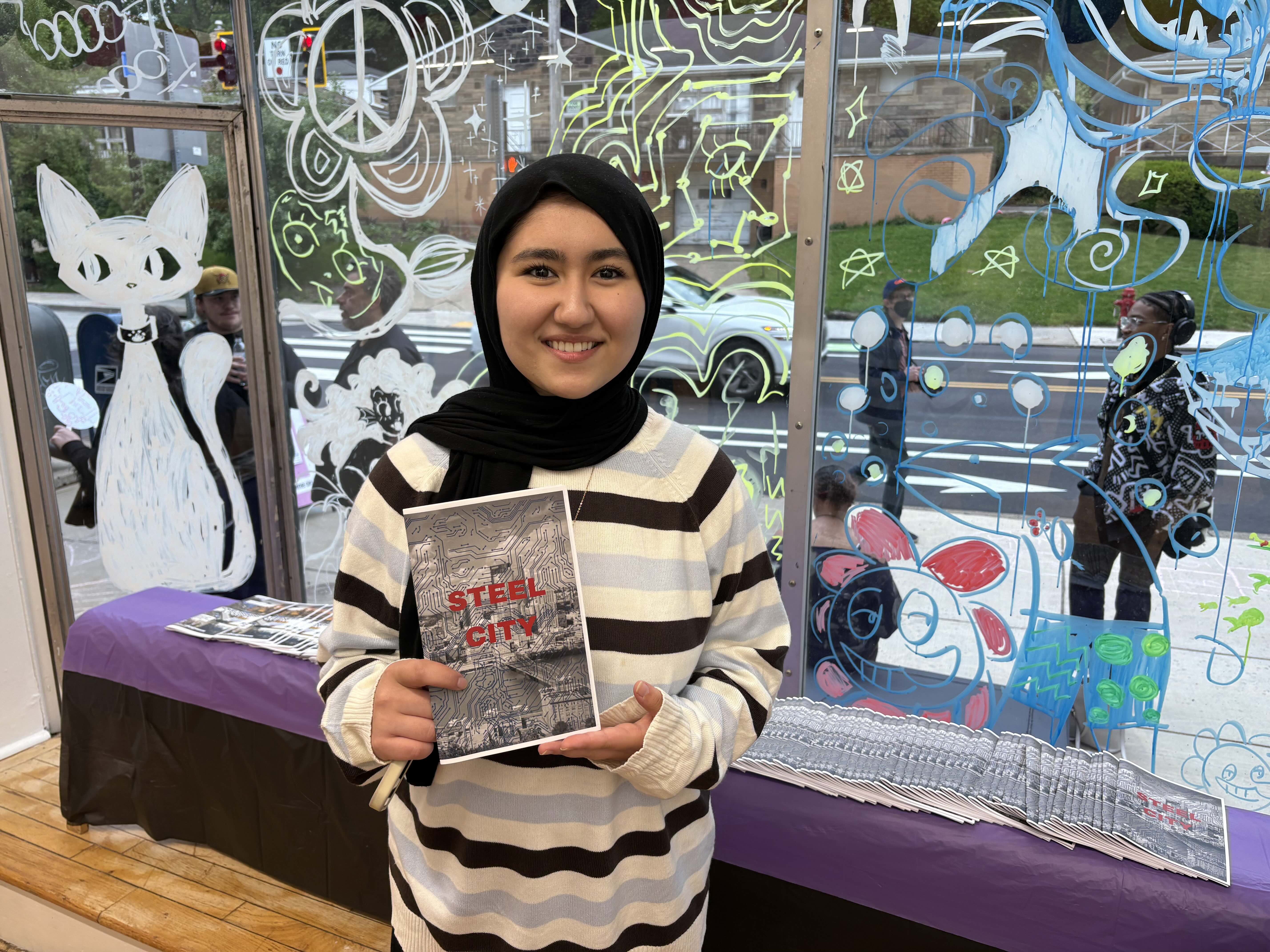 Student holding a small, paper zine.