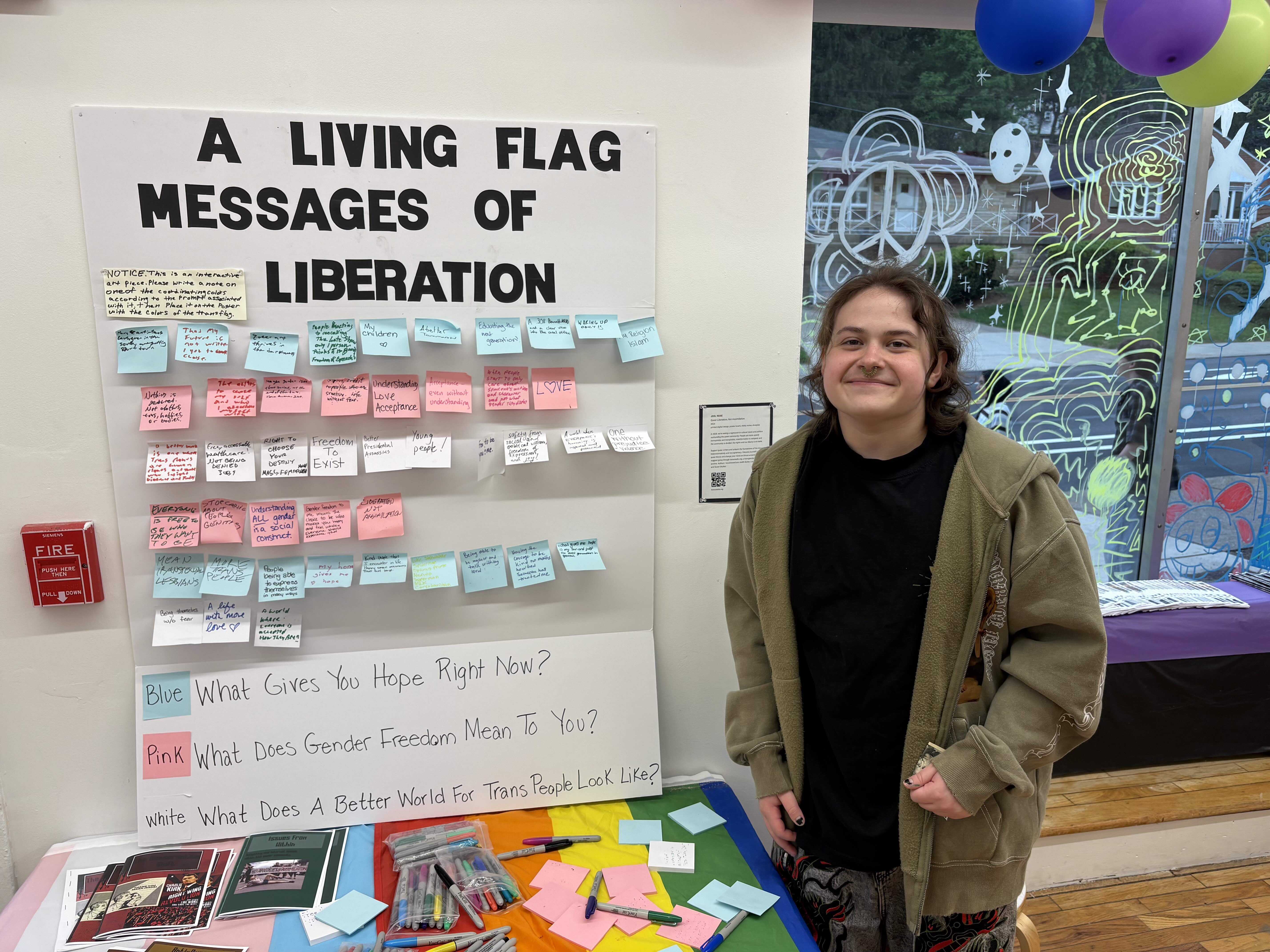 Student standing next to a display board with the words "A Living Flag: Messages of Liberation" across the top.
