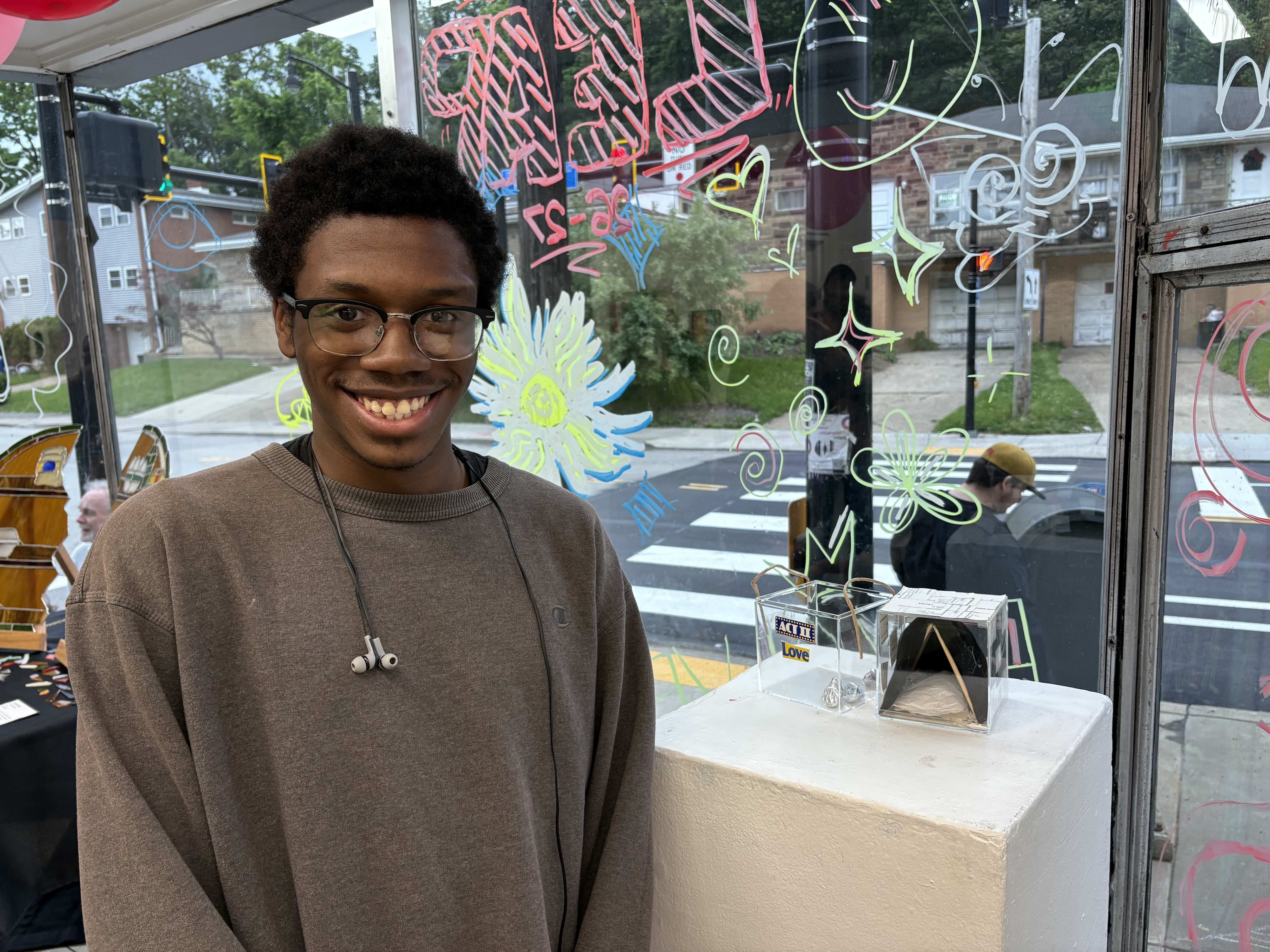 Student smiling next to a small, mixed media sculpture.