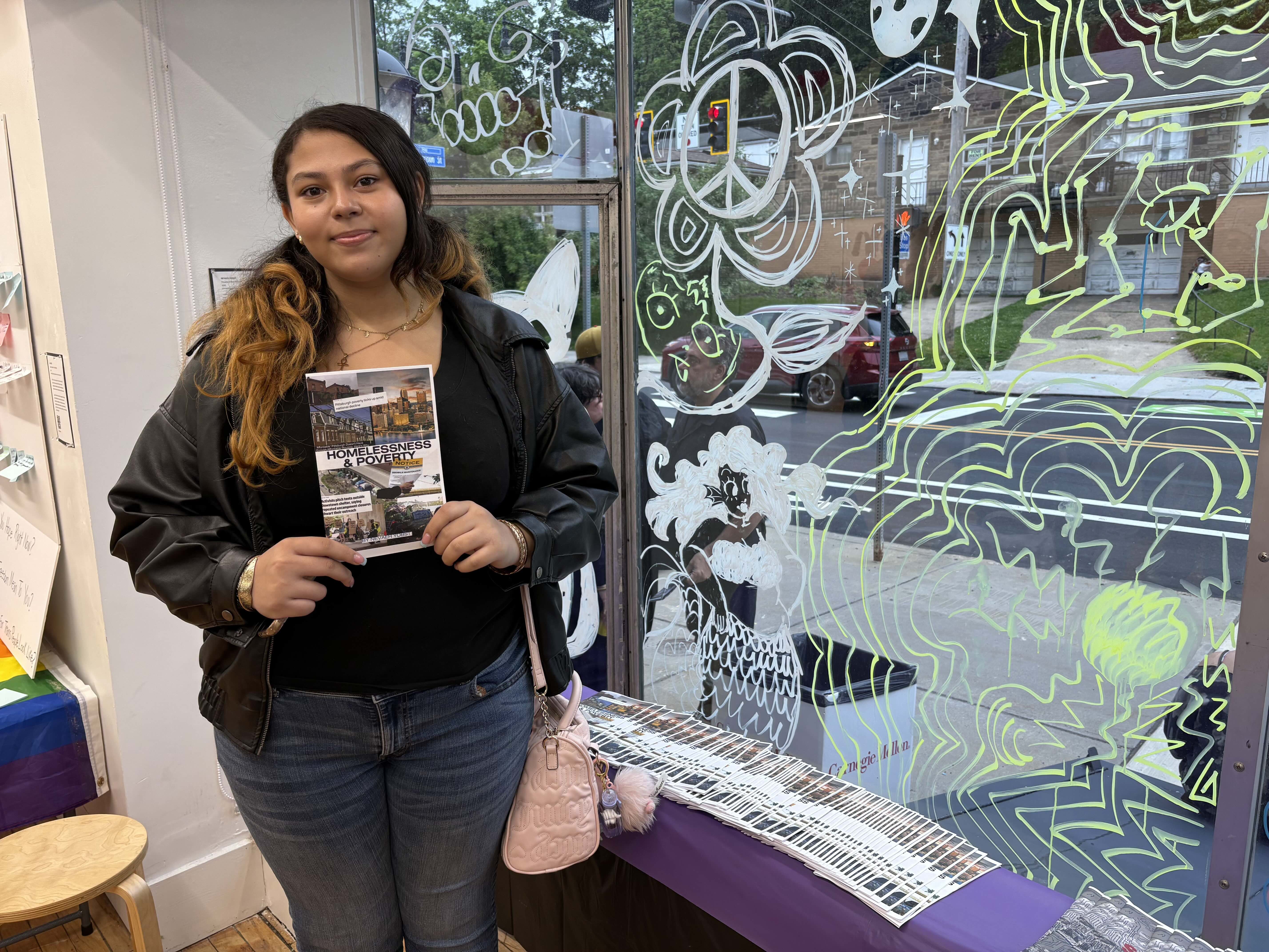 Student holding a small printed zine.