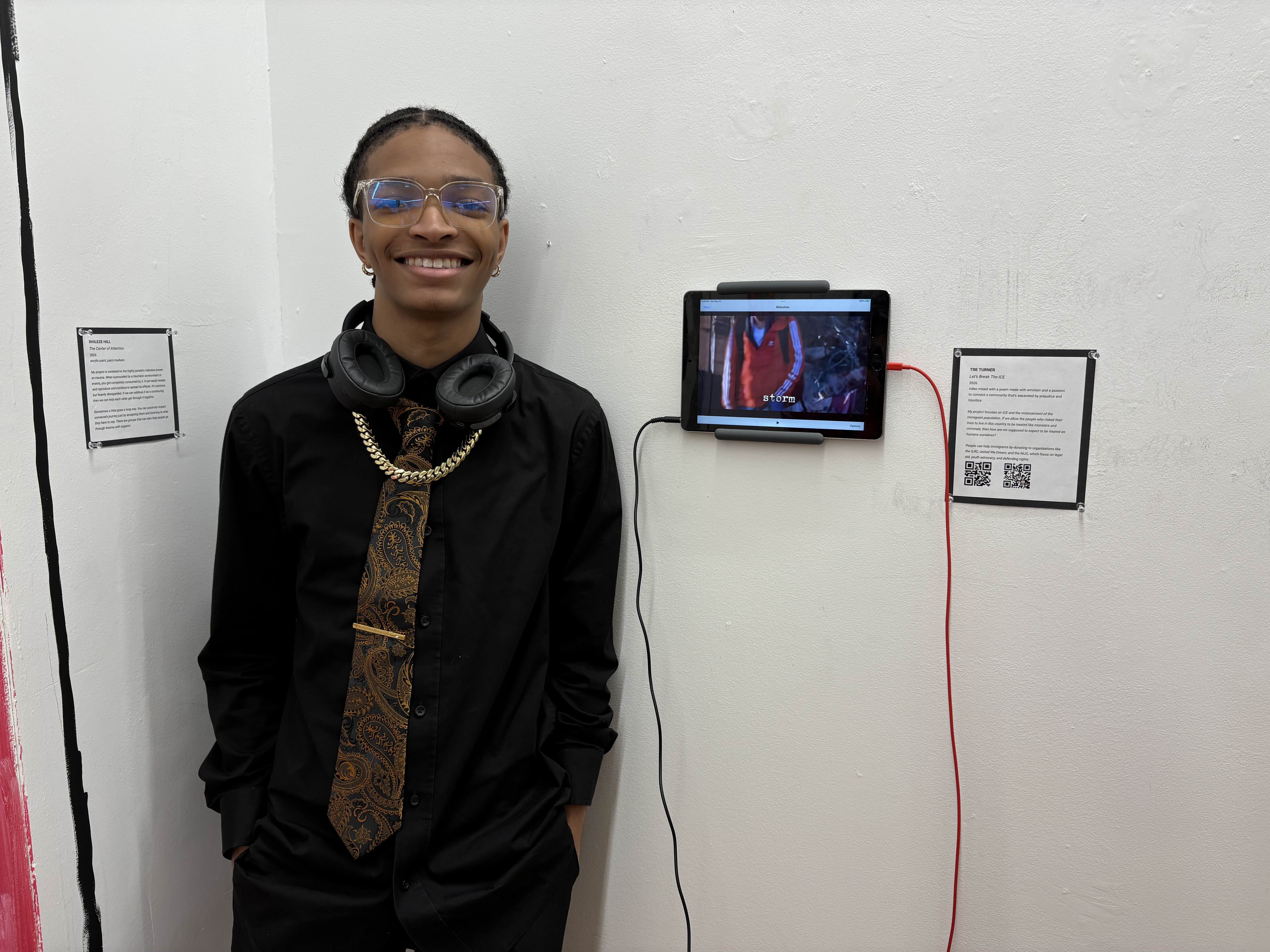 Student standing next to wall-mounted iPad playing a video.