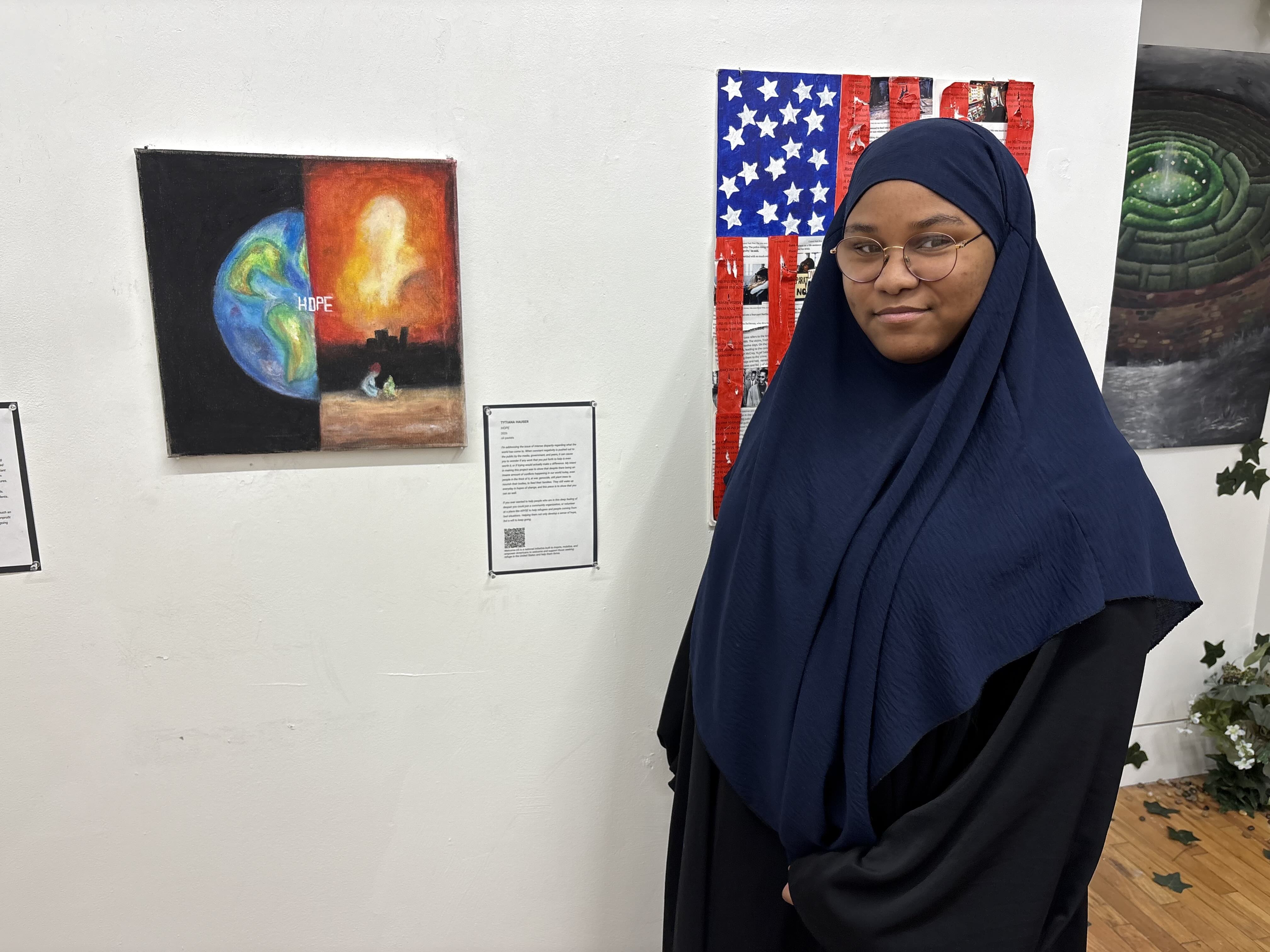 Student standing next to painting split down the center with the Earth on the left and an explosion on the right.