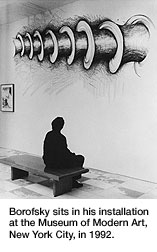 Borofsky sits in front of his artwork