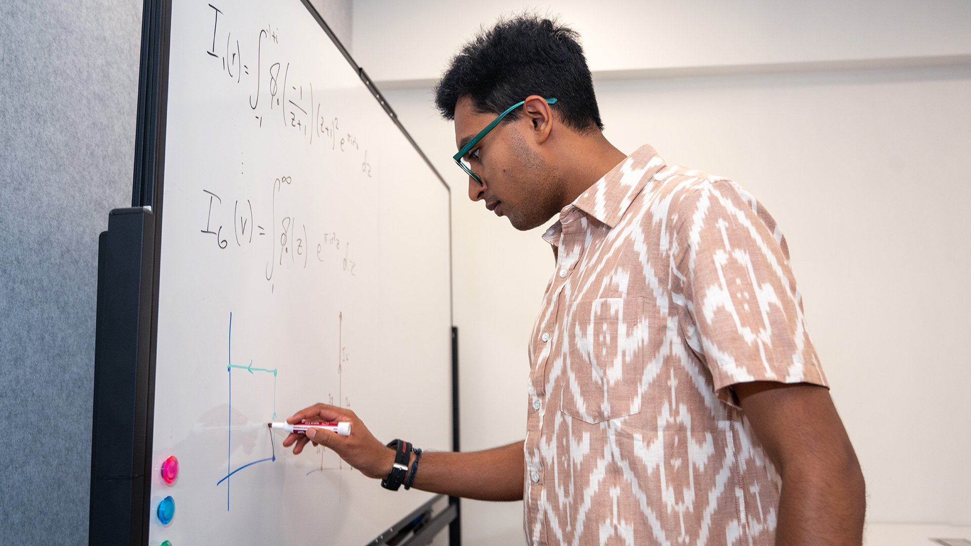 Sidharth Hariharan writes a math equation on a whiteboard.