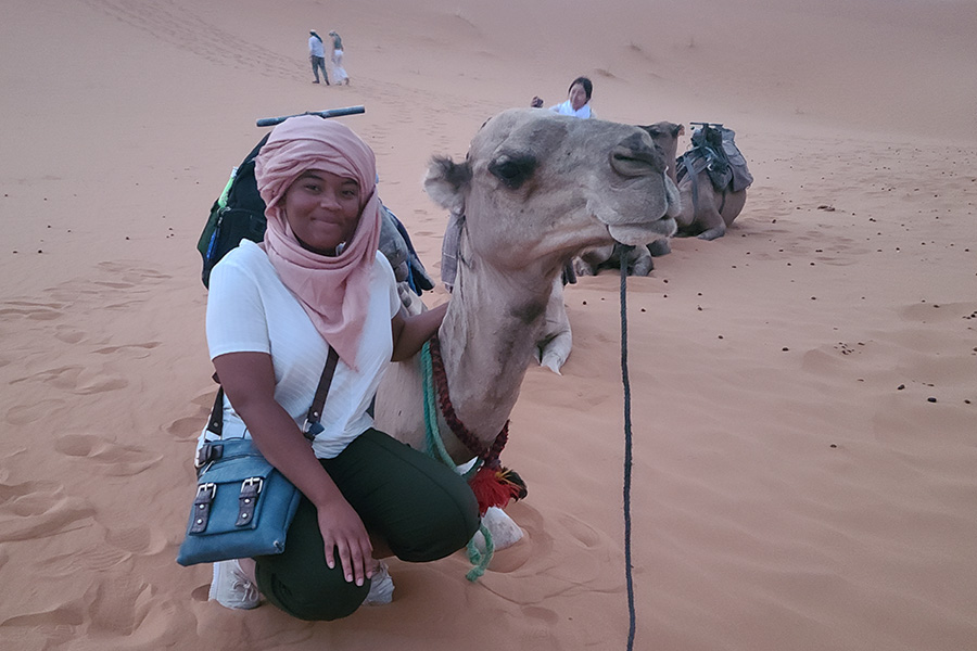 woman kneeling with a camel