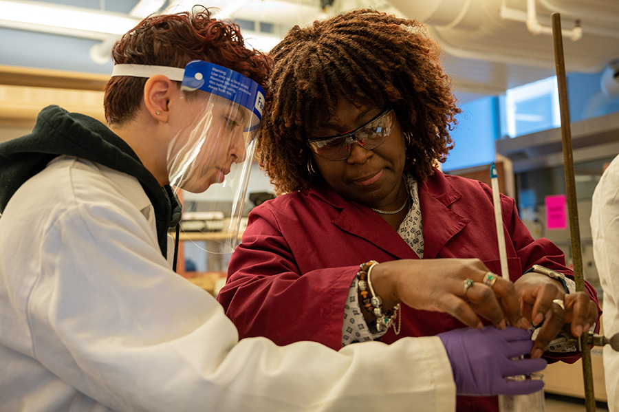 A faculty member stirs a beaker while a student watches