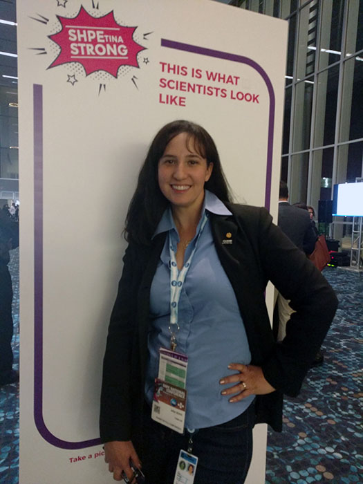 Woman in front of a sign that says this is what a scientist looks like