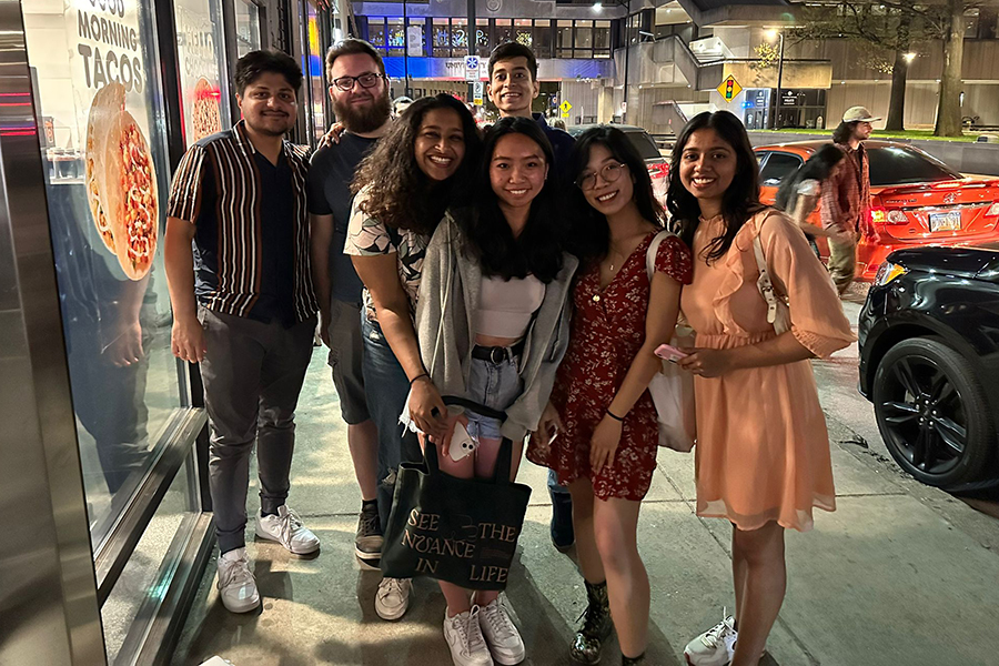 Image of a group of students posing on a sidewalk at night