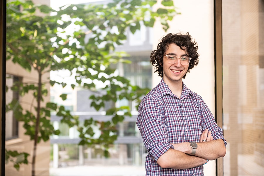 male student standing with arms crossed