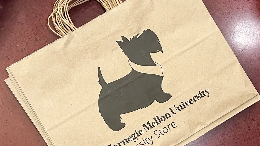 a paper bag with a CMU Scotty dog printed on it. The text reads "Carnegie Mellon University University Store."