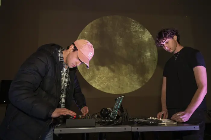 two students mixing audio in front of moon