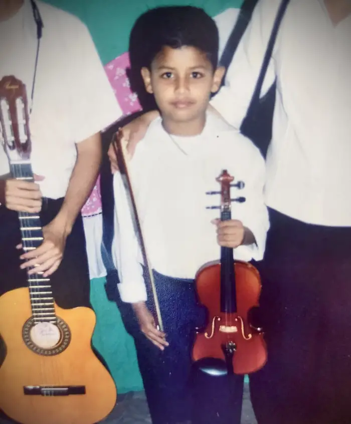 Jorge Vera as a boy holding a violin. 