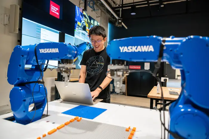 Two blue robotic arms build a lego guitar.