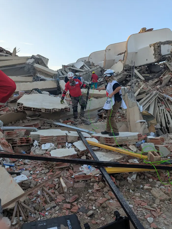 People stand amid collapsed buildings with snake robots following two massive earthquakes that devastated cities. 