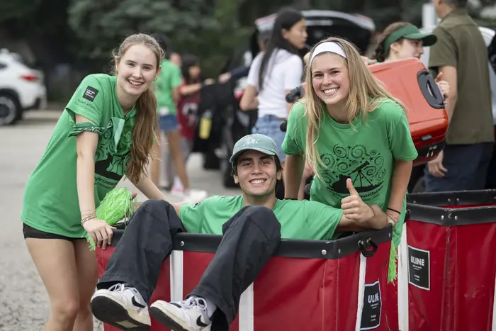 Two students push a third in a move-in cart. 