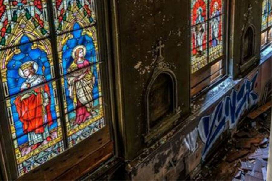 disrepair on wall featuring stained glass windows inside church