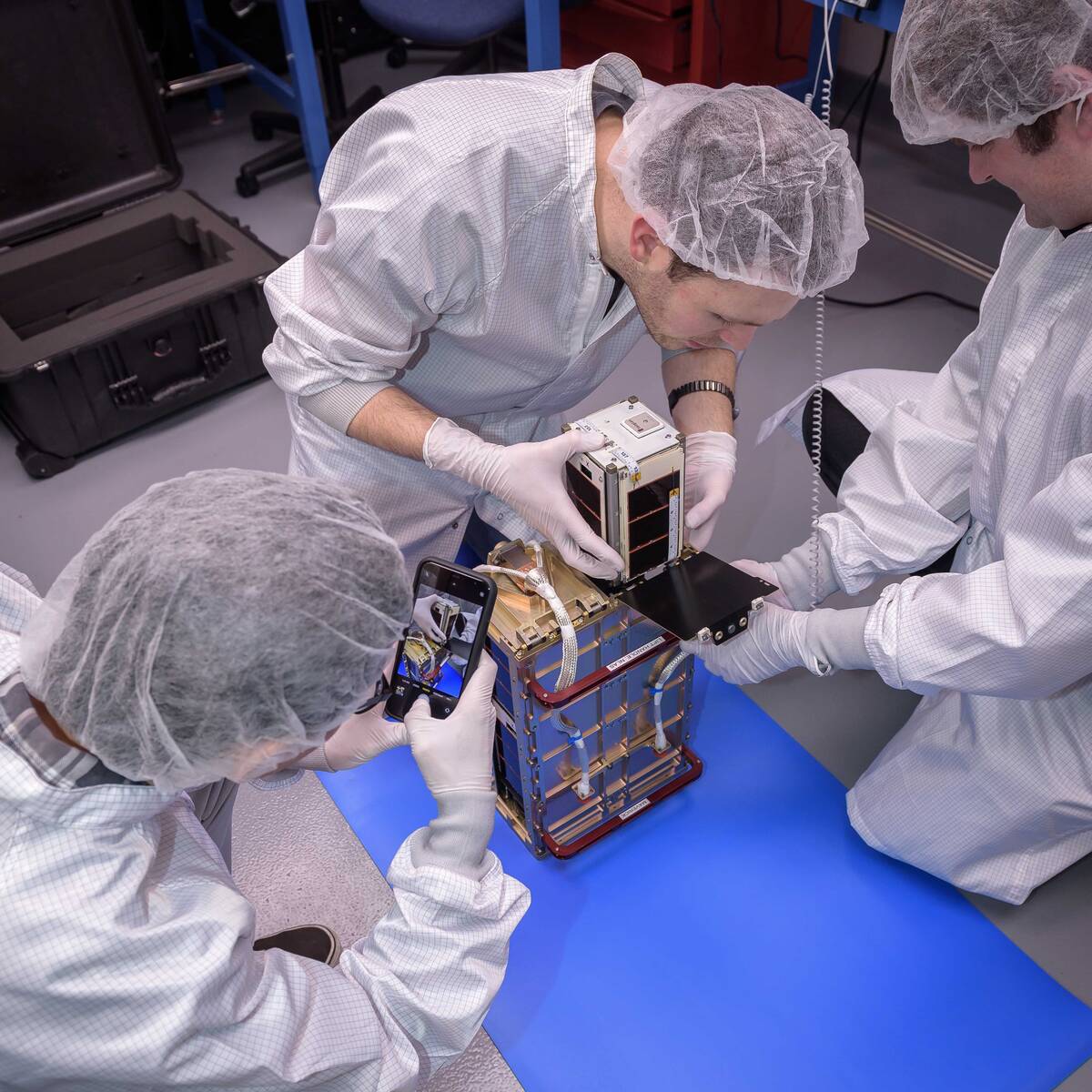 Max Holliday, middle, installs one of the four PyCubed-Based CubeSat (PY4) spacecraft into the Small Satellites Dispenser.