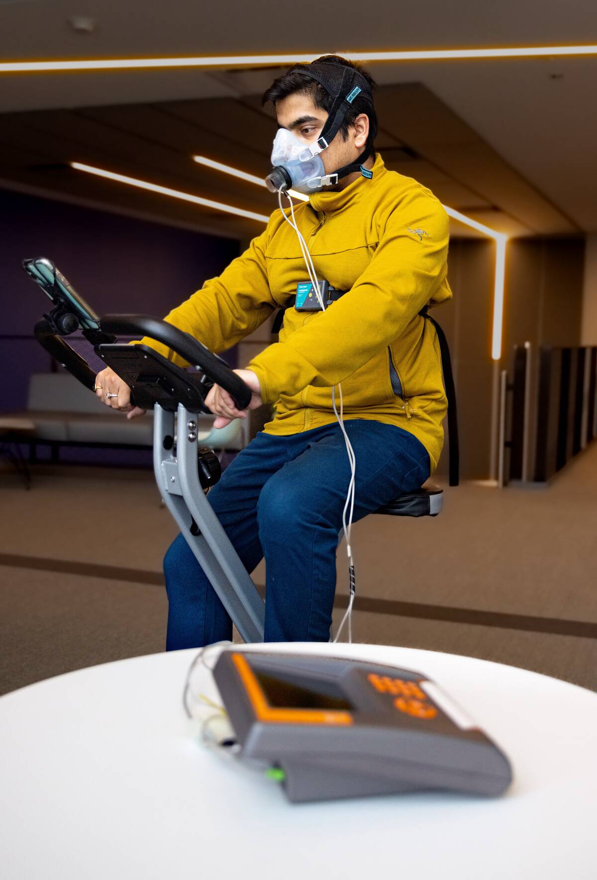 A man on a treadmill has a mask over his nose and mouth to capture his breathing.