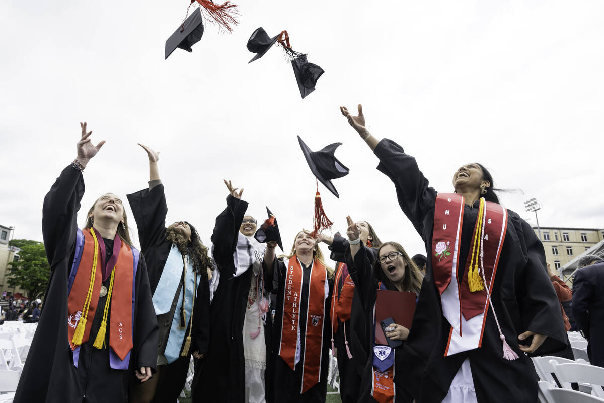 Graduates throw their caps in the air. 