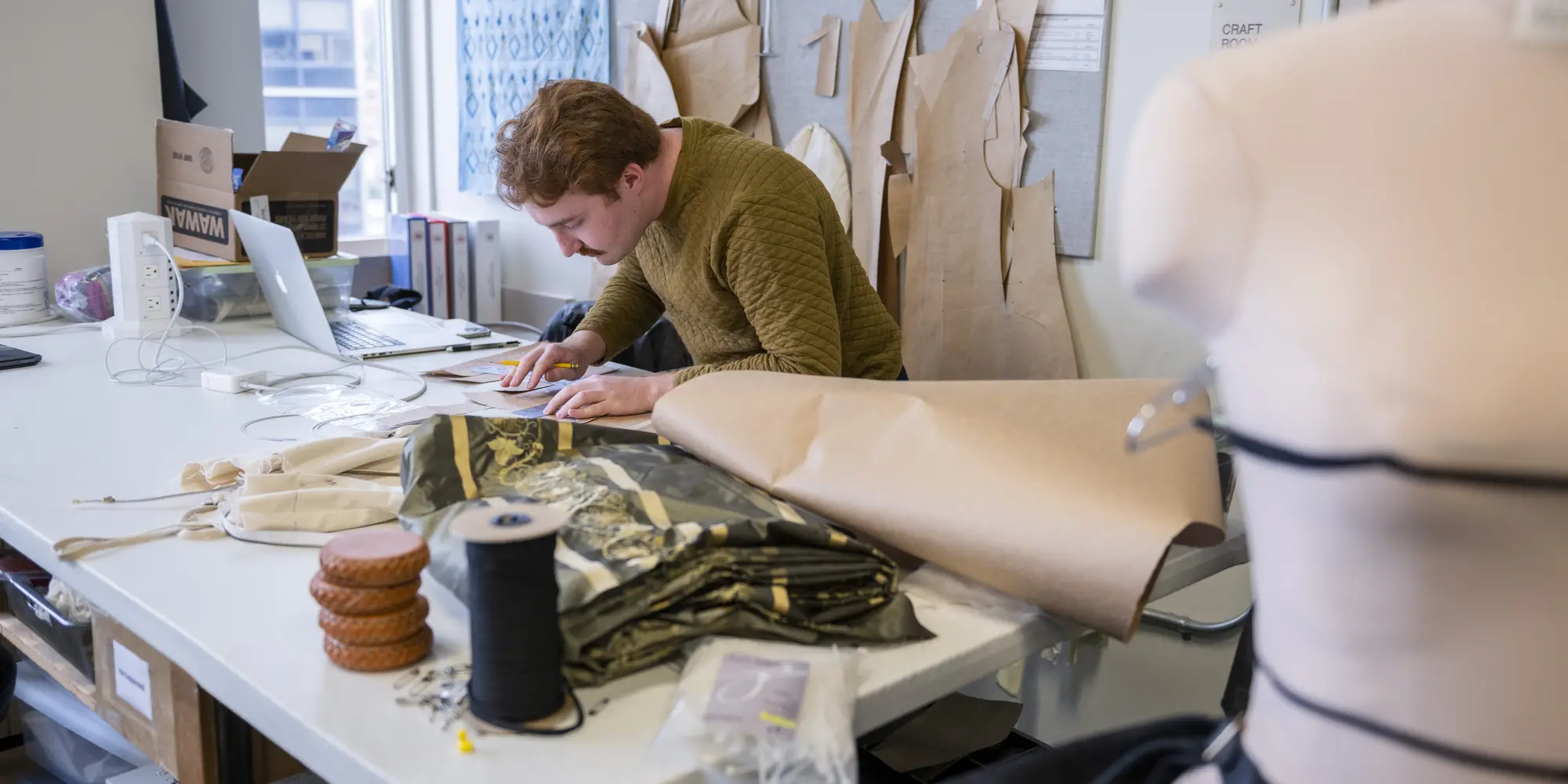 students hunched over table making paper costume patterns