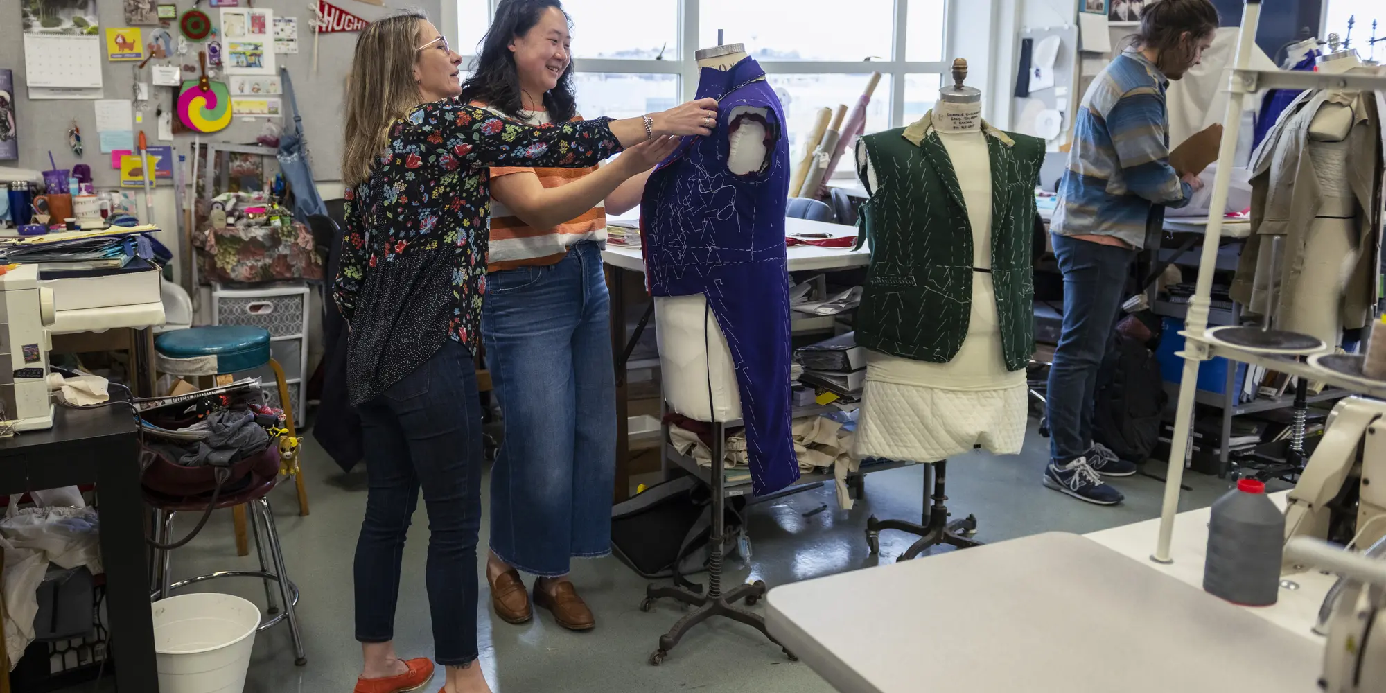 Tiia Lager helping student adjust blue costume on mannequin torso