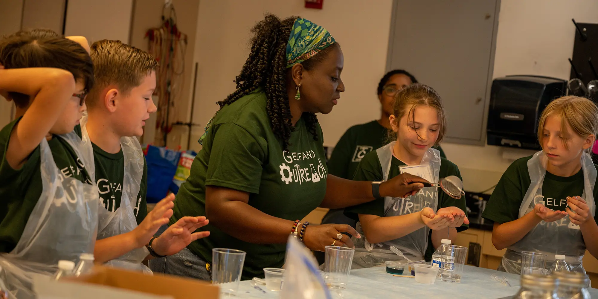 Woman working at lab table with children on either side