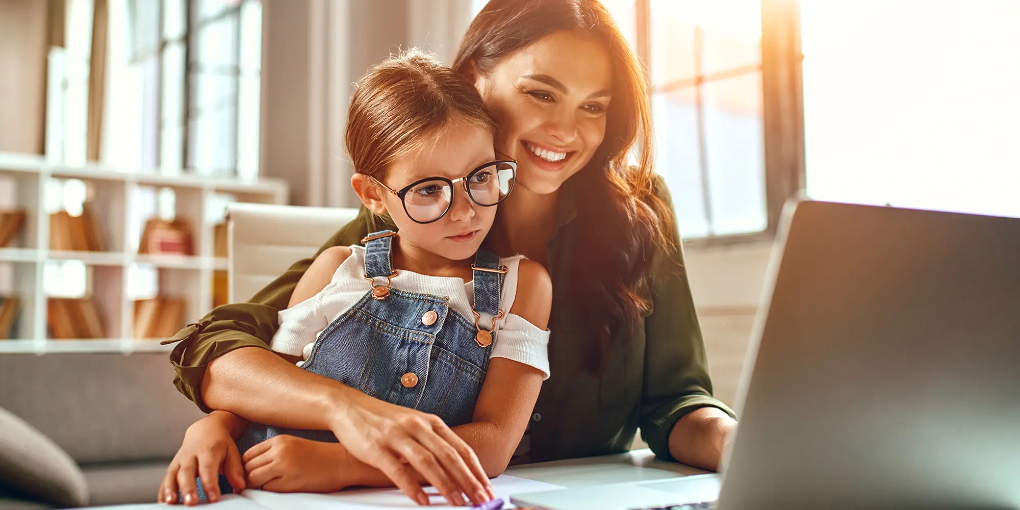 Mother and daughter seated looking at laptop screen