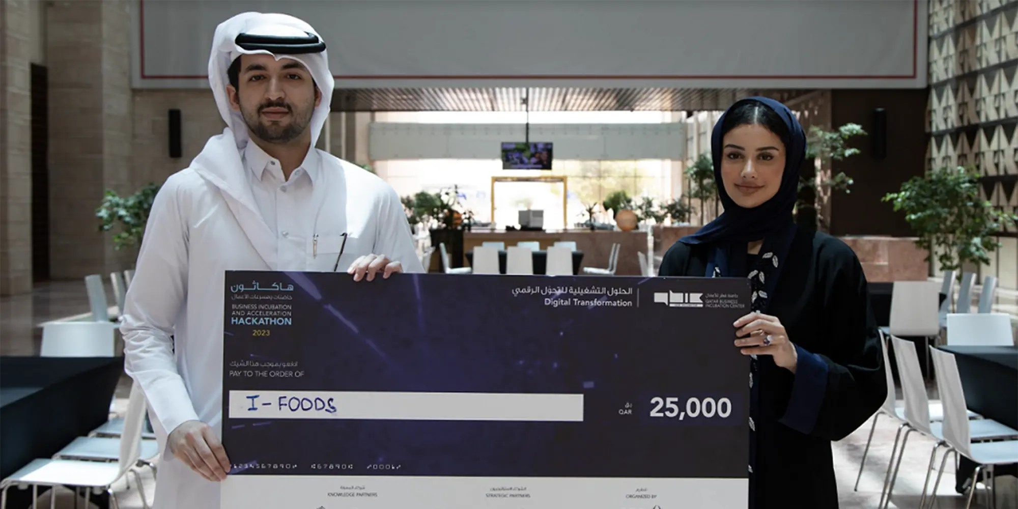 Two Qatar students holding large check