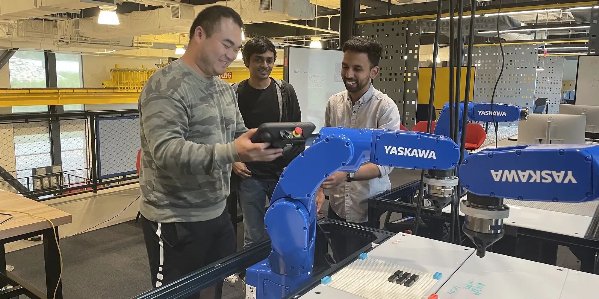 three people in lab standing around a robotic arm