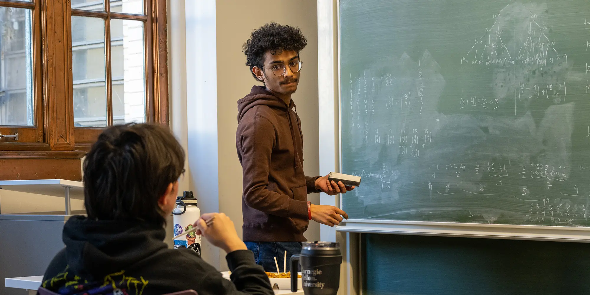 student at chalk board consulting student seated