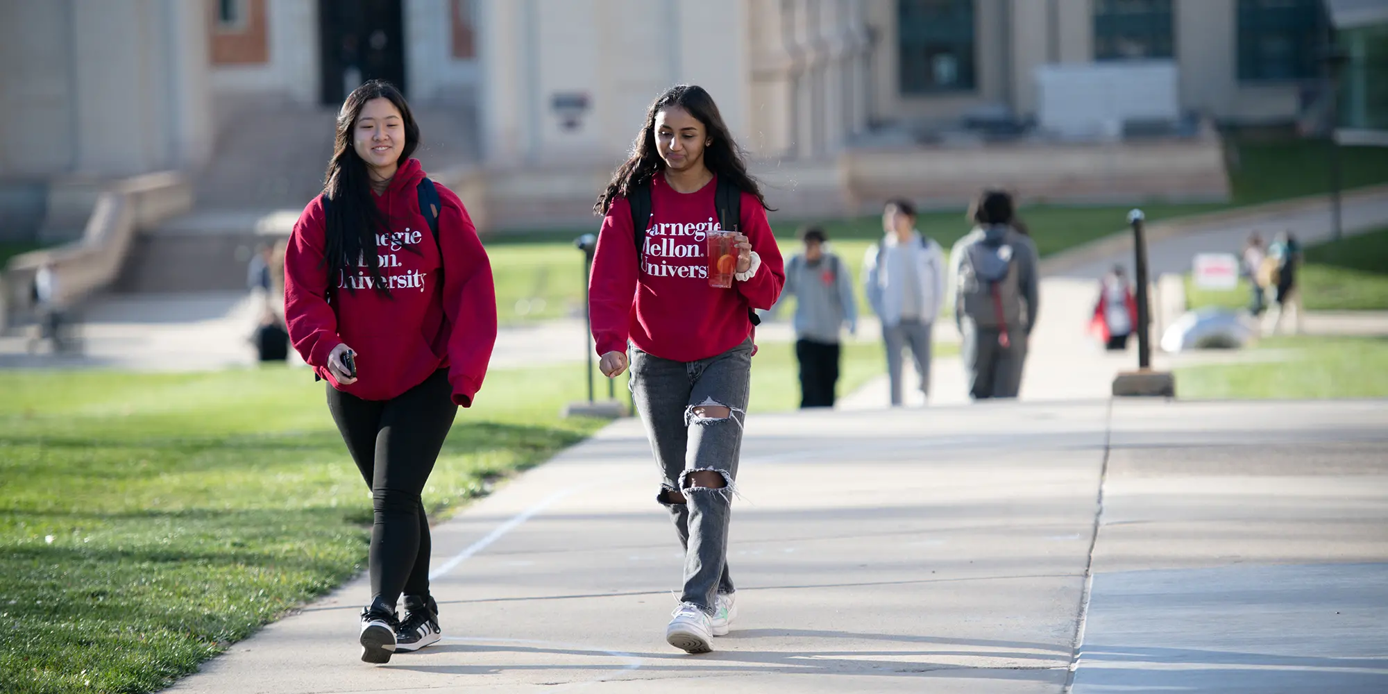 two girls in red CMU hoodies walking on campus