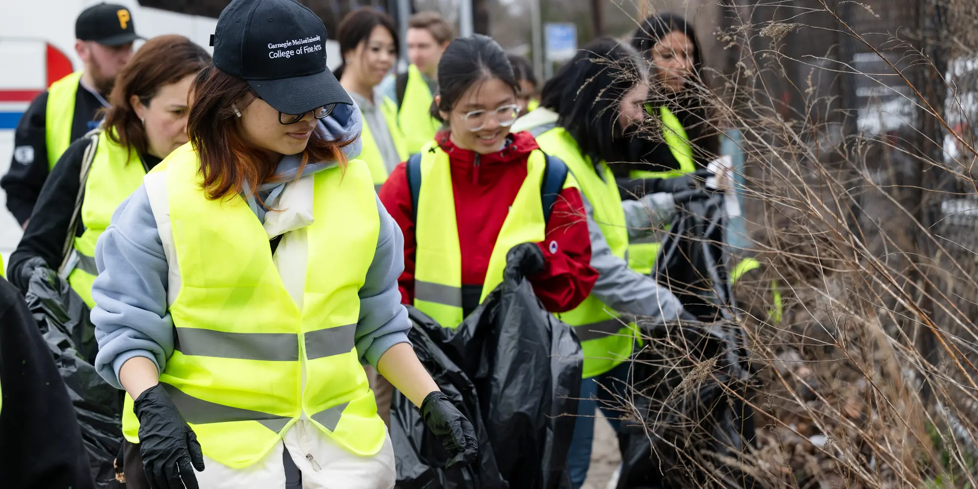 students in yellow safety vests picking up trash