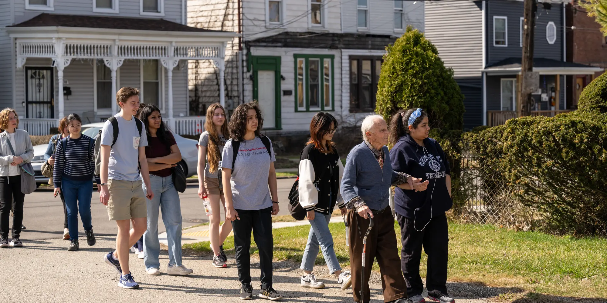 group of people walking through neighborhood on a sunny day