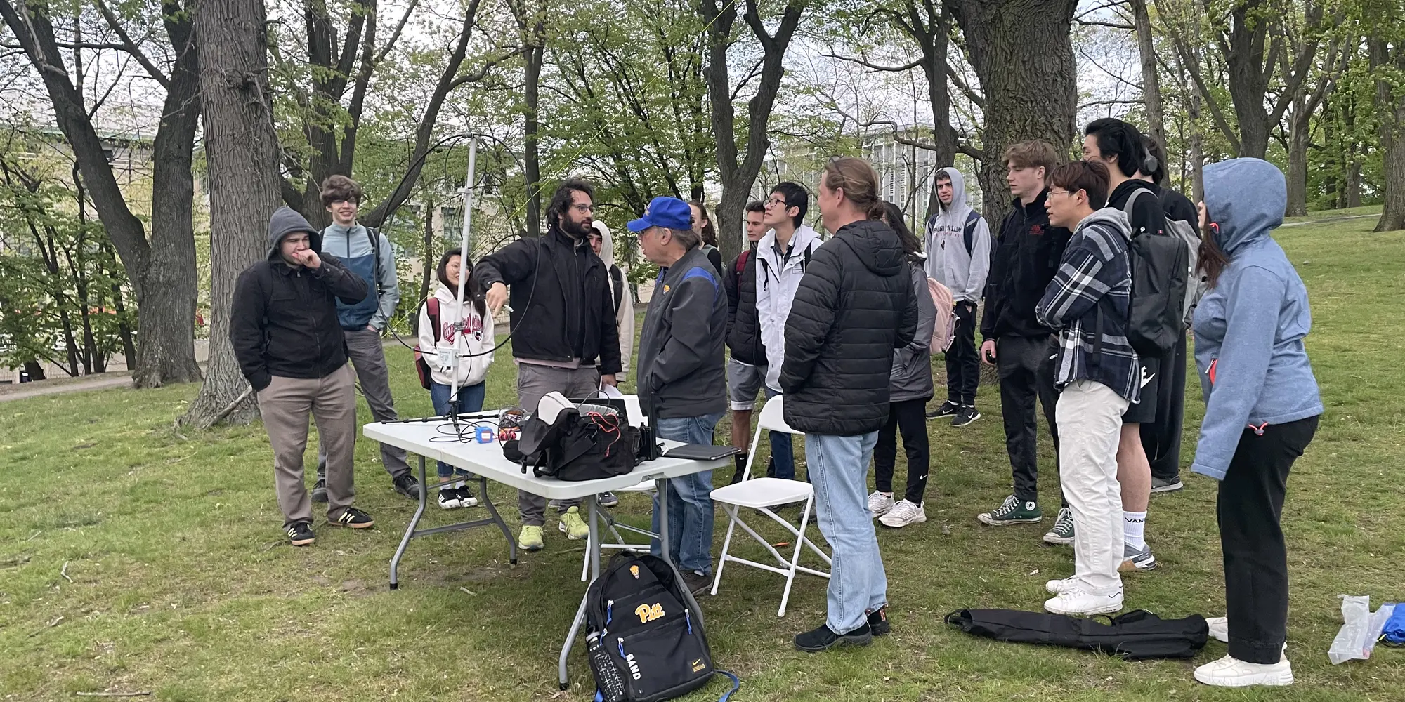 teacher instructing class outdoors under the trees