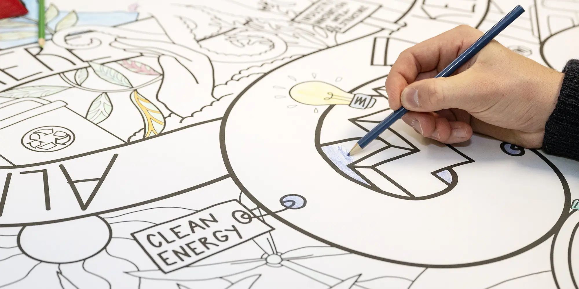 A person colors in a large black and white doodle.