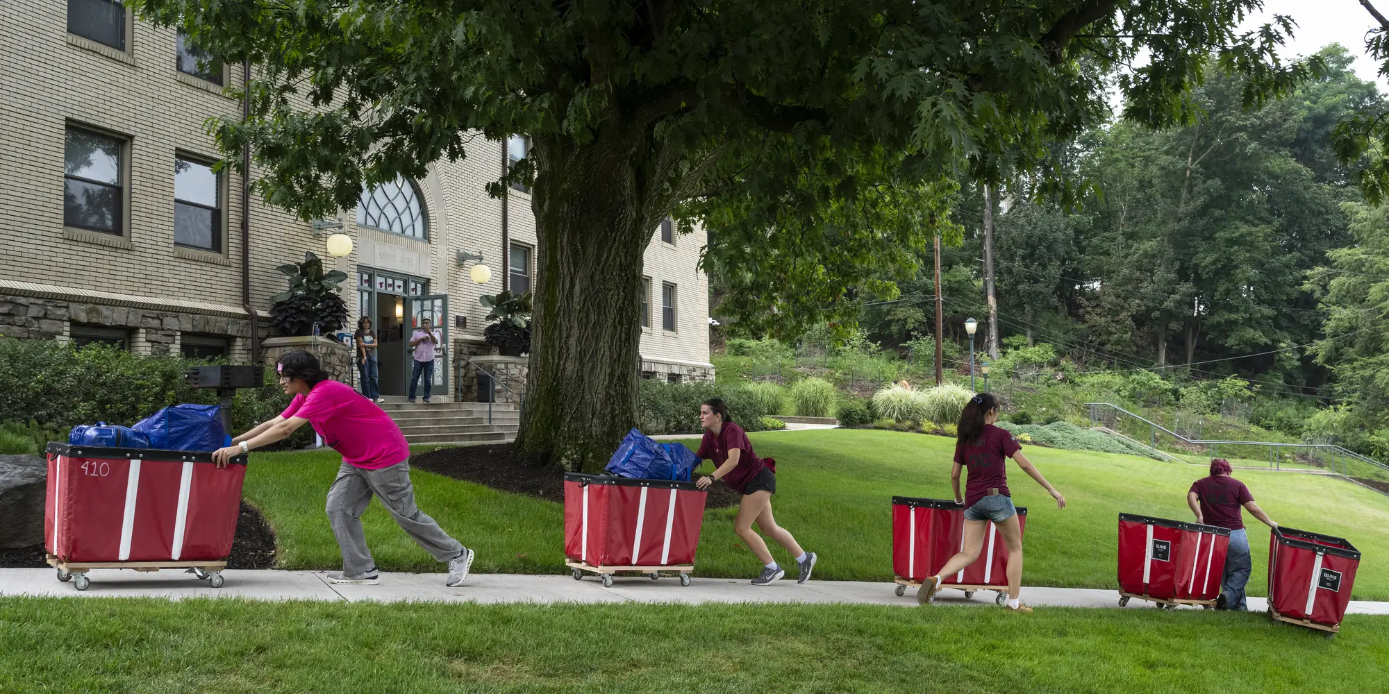 Students push red loading carts into a CMU dorm. 