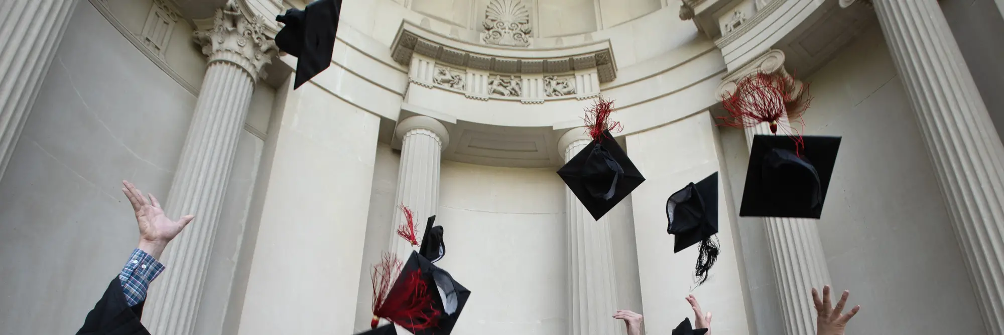 CMU grads throw their caps into the air in front of the College of Fine Arts building.