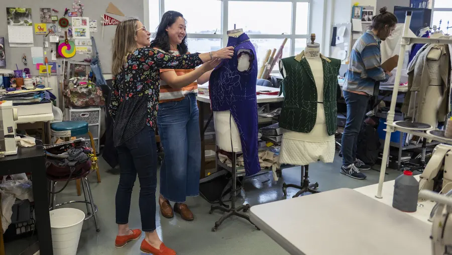 Tiia Lager helping student adjust blue costume on mannequin torso