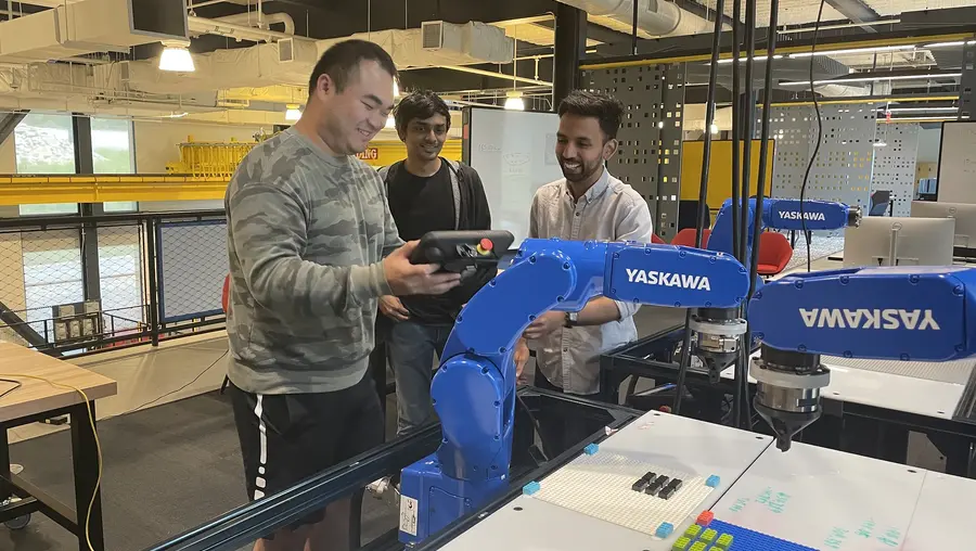 three people in lab standing around robotic arm