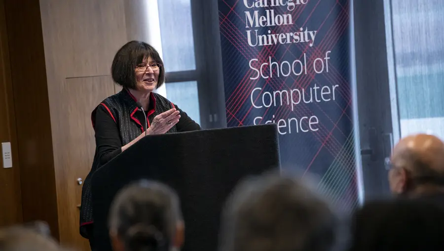 Lenore Blum standing at a podium.