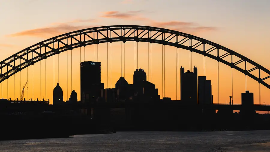 The city of Pittsburgh, seen silhouetted through a bridge. 
