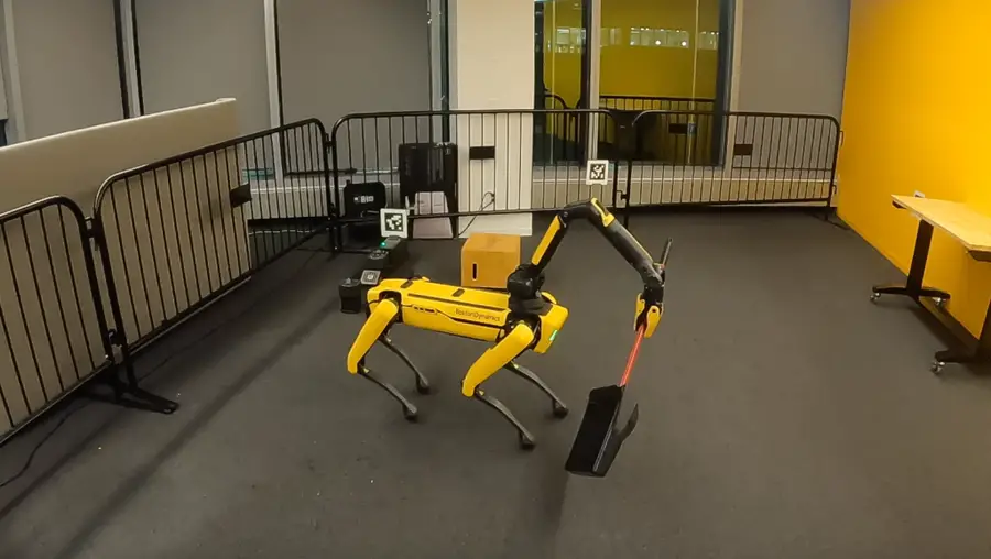 Four-legged robot holding a broom to sweep
