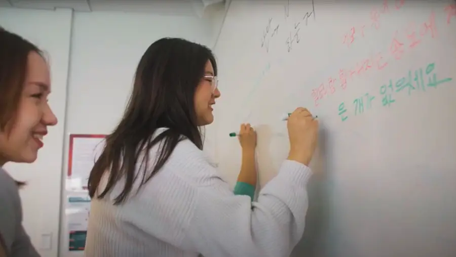 Students writing in Korean on a whiteboard.