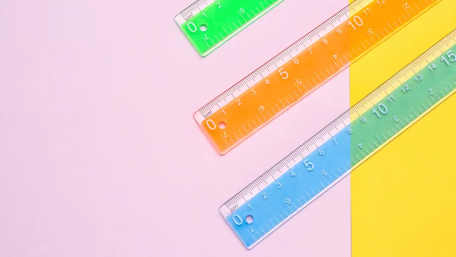 three plastic rules placed diagonally on a pink and yellow background