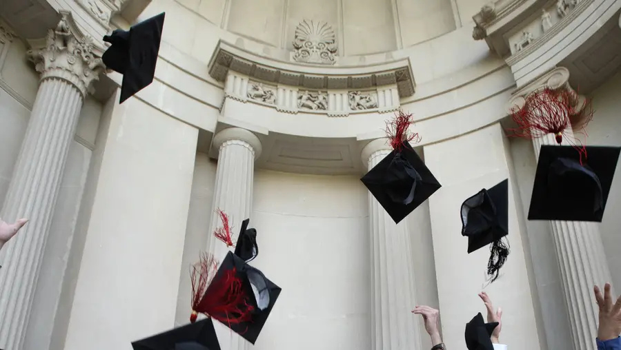 CMU grads throw their caps into the air in front of the College of Fine Arts building.