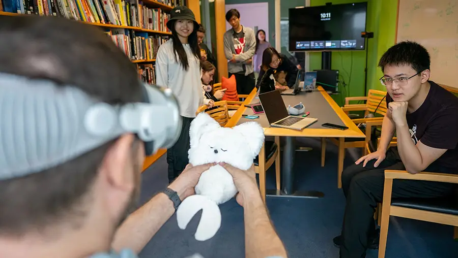 The Physical Presence Pet team looks on while a guest playtests their project.