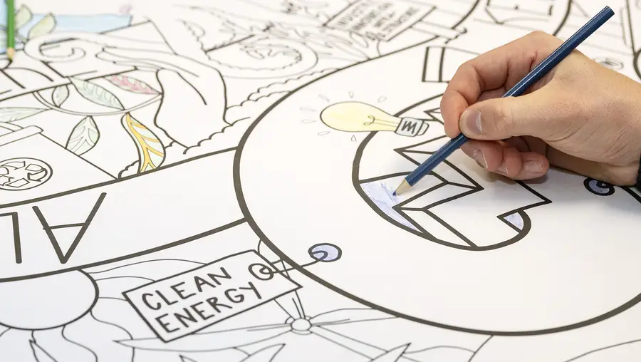 A person colors in a large black and white doodle. 