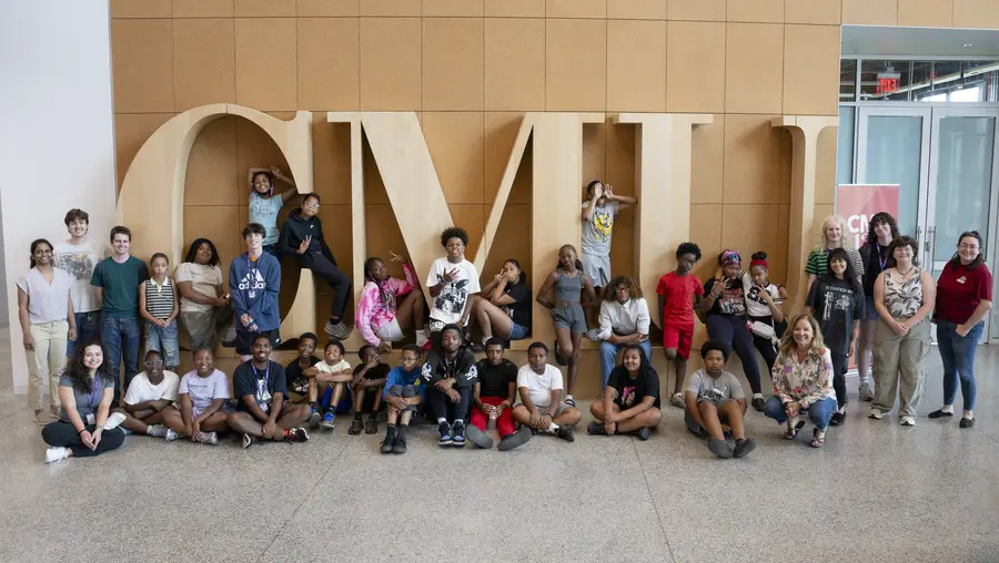 students standing in front of large wooden CMU letters
