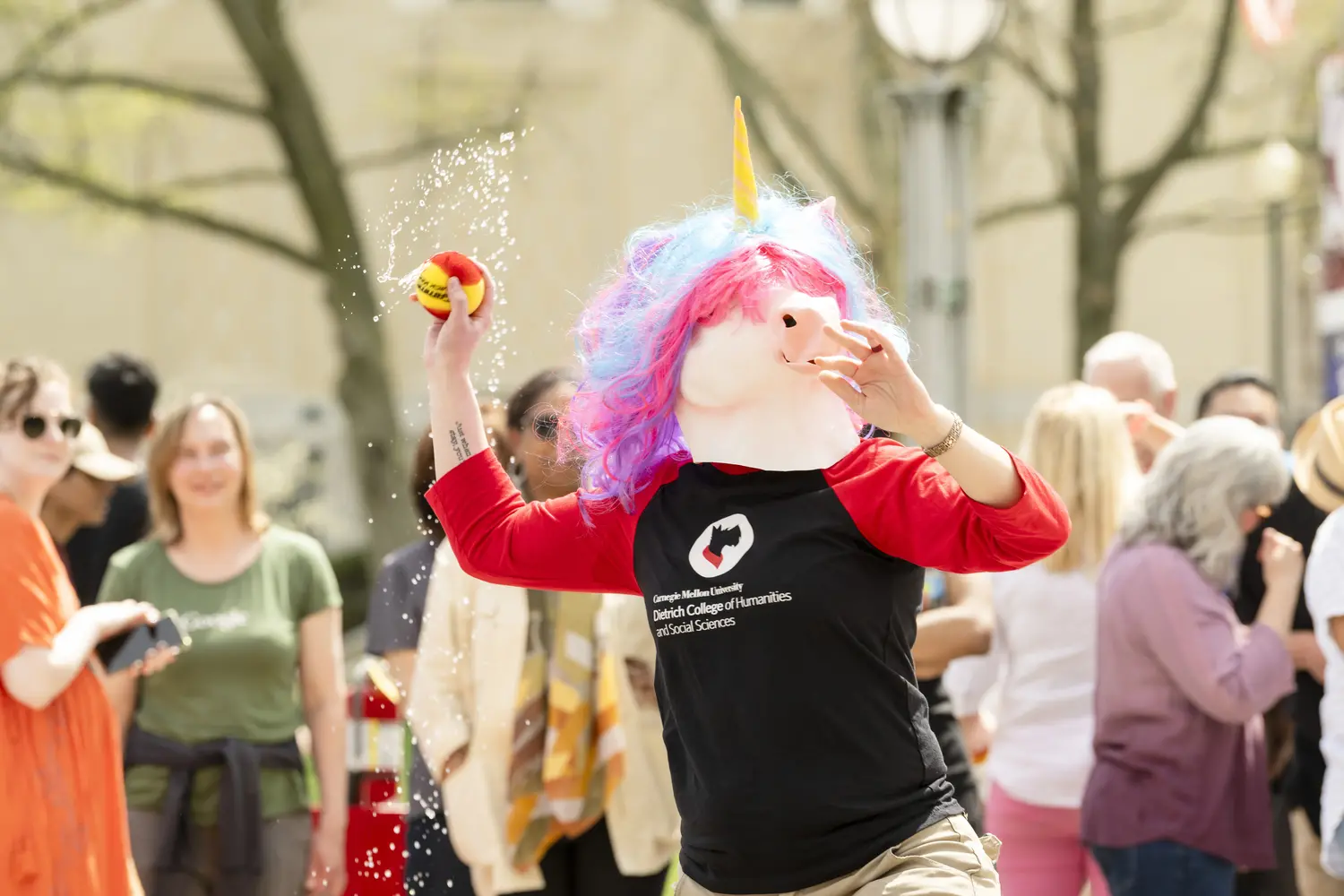 A person in a unicorn mask throws a ball