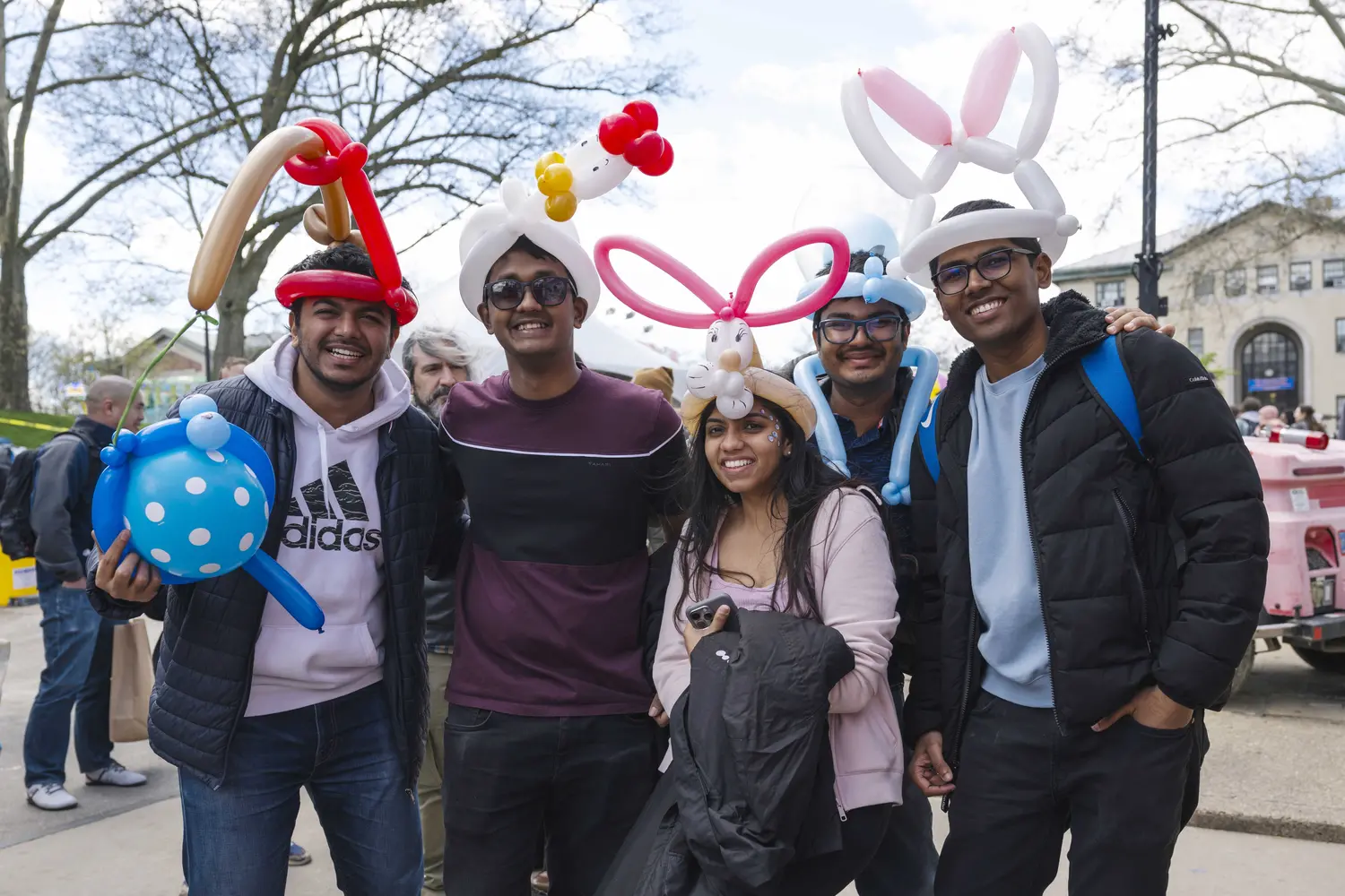 Carnival-goers happily wear ballon animal hats.
